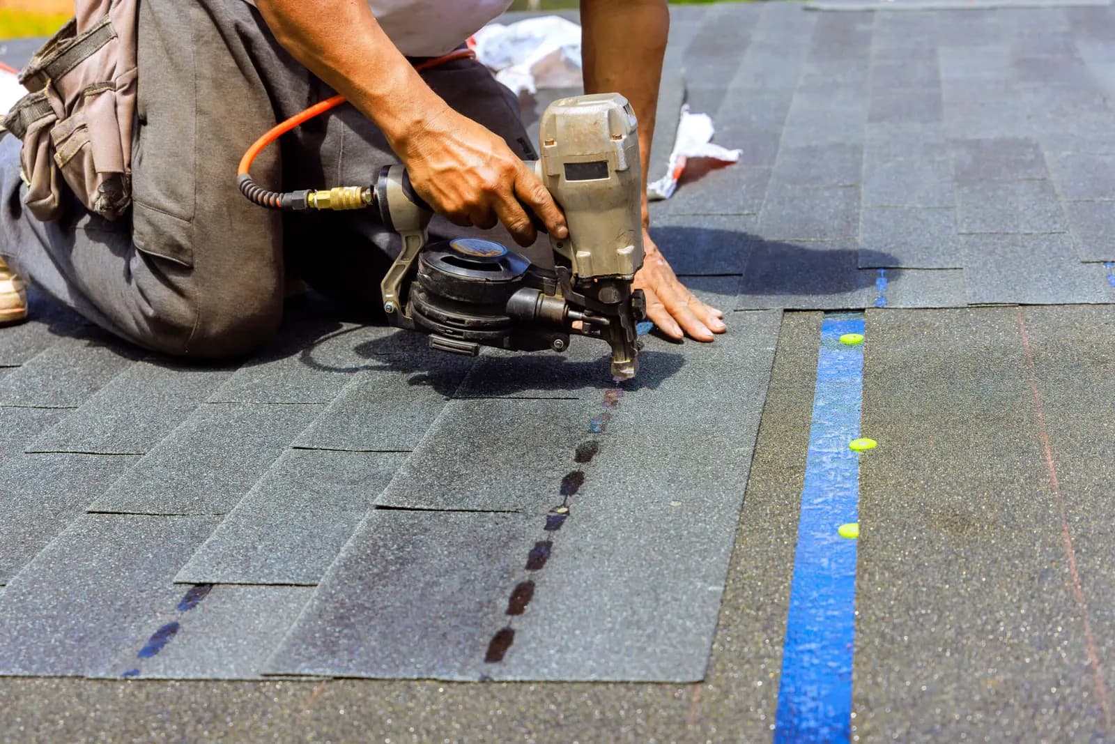 Roofer repairing shingles with a nail gun